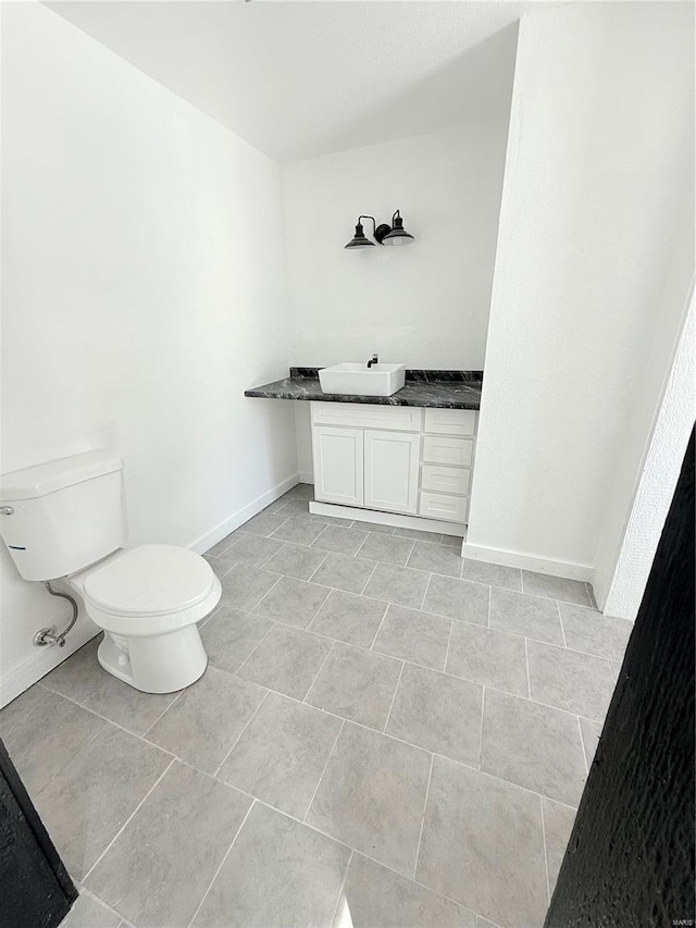 bathroom with toilet, vanity, baseboards, and tile patterned flooring