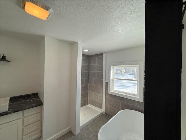 full bathroom featuring vanity, tile patterned floors, a textured ceiling, a shower stall, and a freestanding bath