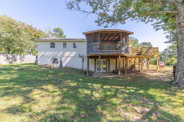 back of property with a sunroom, a deck, and a yard