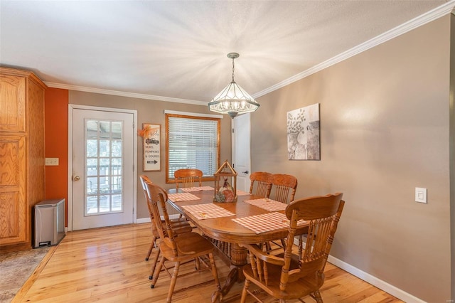 dining area featuring an inviting chandelier, light wood-type flooring, and crown molding