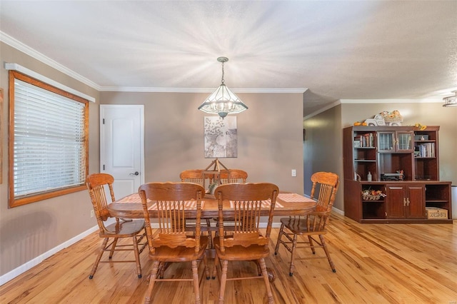 dining area featuring ornamental molding, an inviting chandelier, and light hardwood / wood-style flooring