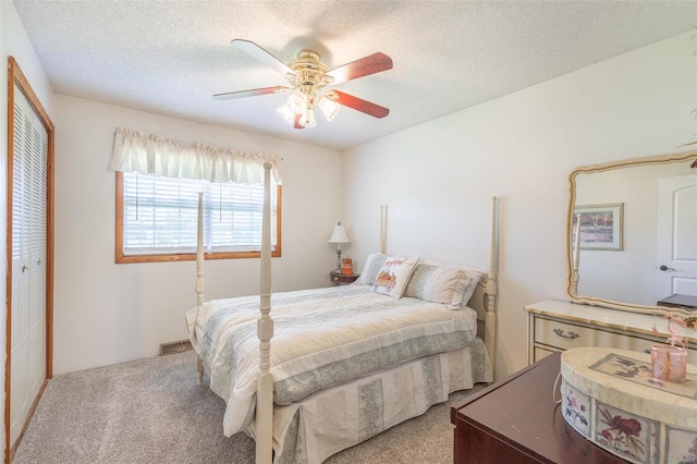 bedroom with a closet, ceiling fan, light colored carpet, and a textured ceiling