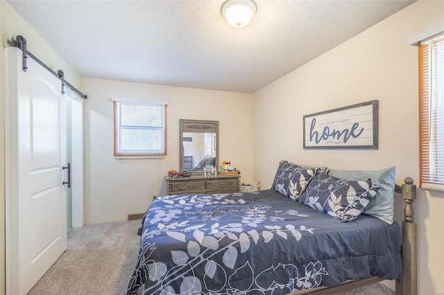 carpeted bedroom with a barn door and a textured ceiling