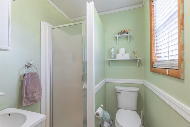 bathroom with a textured ceiling, ornamental molding, toilet, sink, and an enclosed shower