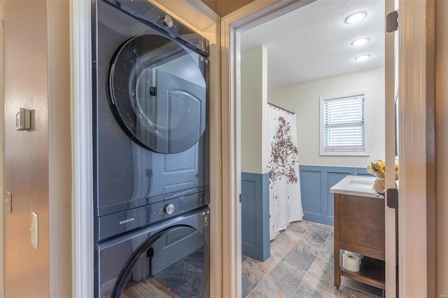 clothes washing area featuring a textured ceiling and stacked washer and clothes dryer