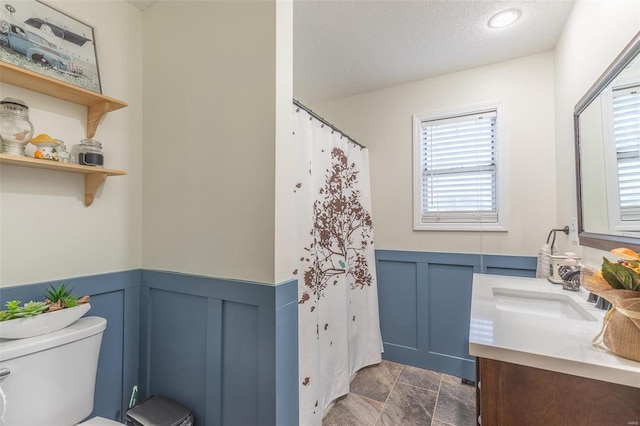 bathroom featuring a textured ceiling, vanity, toilet, and a shower with curtain