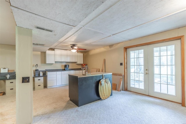 kitchen featuring light carpet, white cabinetry, ceiling fan, and french doors