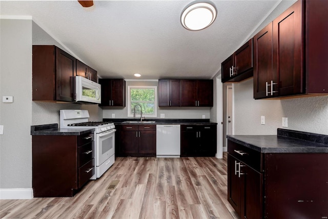 kitchen with light wood-type flooring, white appliances, a textured ceiling, and sink