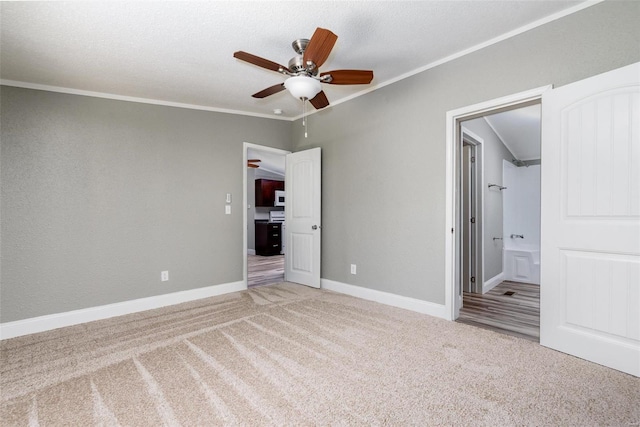 unfurnished bedroom with ceiling fan, carpet floors, crown molding, and ensuite bathroom