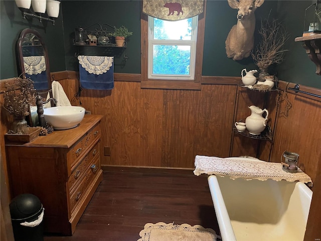 bathroom with wood walls, vanity, a bathing tub, and hardwood / wood-style flooring