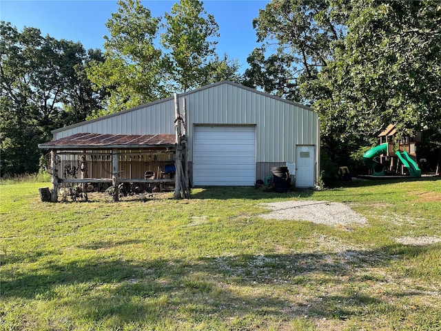 view of outbuilding featuring a garage, a playground, and a yard