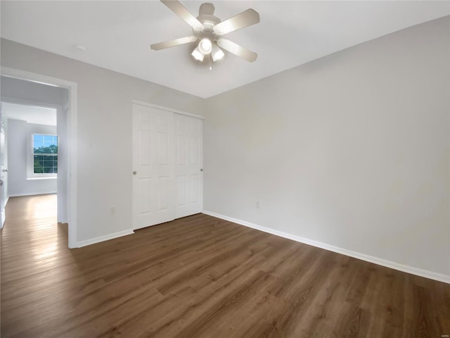 unfurnished bedroom featuring dark hardwood / wood-style flooring, ceiling fan, and a closet