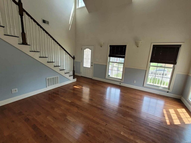 unfurnished living room featuring a high ceiling, hardwood / wood-style floors, and a wealth of natural light