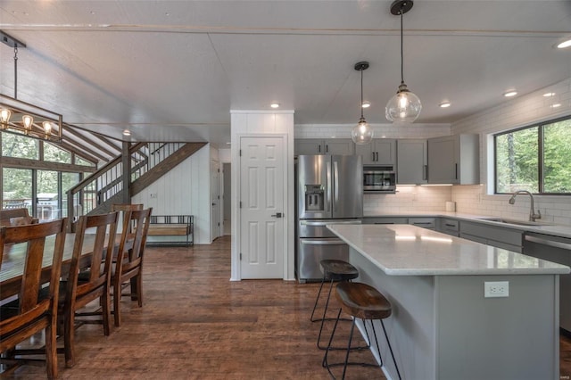 kitchen featuring appliances with stainless steel finishes, a kitchen island, dark hardwood / wood-style flooring, pendant lighting, and sink