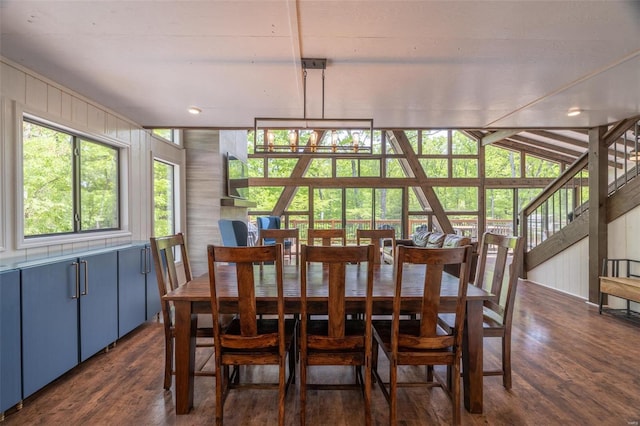 dining area with an inviting chandelier, wooden walls, lofted ceiling, and dark hardwood / wood-style floors