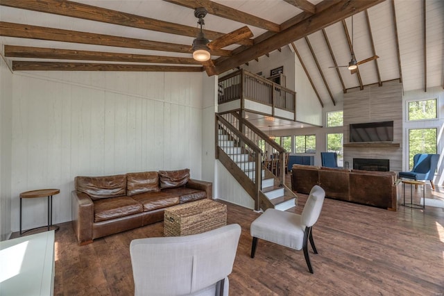 living room featuring beamed ceiling, dark hardwood / wood-style floors, high vaulted ceiling, a large fireplace, and ceiling fan