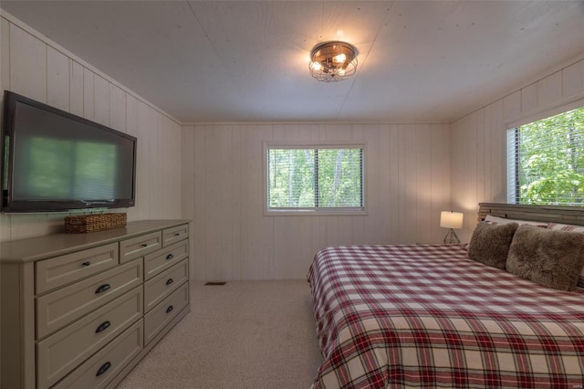 carpeted bedroom featuring multiple windows and wooden walls