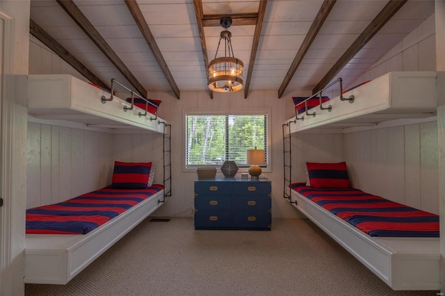 unfurnished bedroom with beam ceiling, wood walls, and carpet flooring