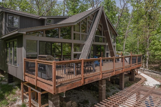 rear view of property with a wooden deck and a sunroom