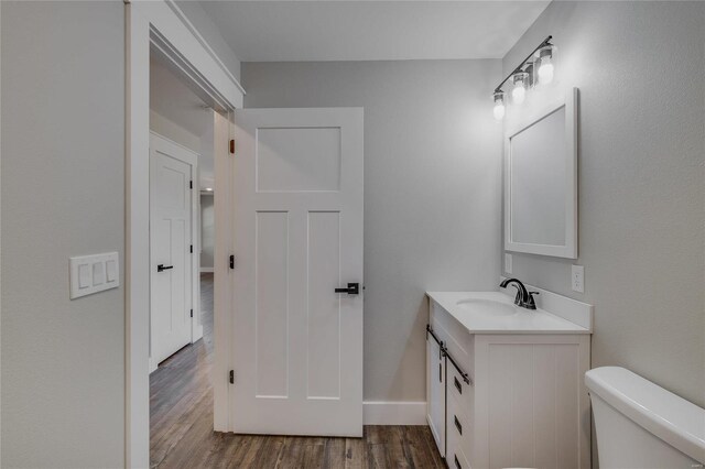 bathroom featuring wood-type flooring, vanity, and toilet