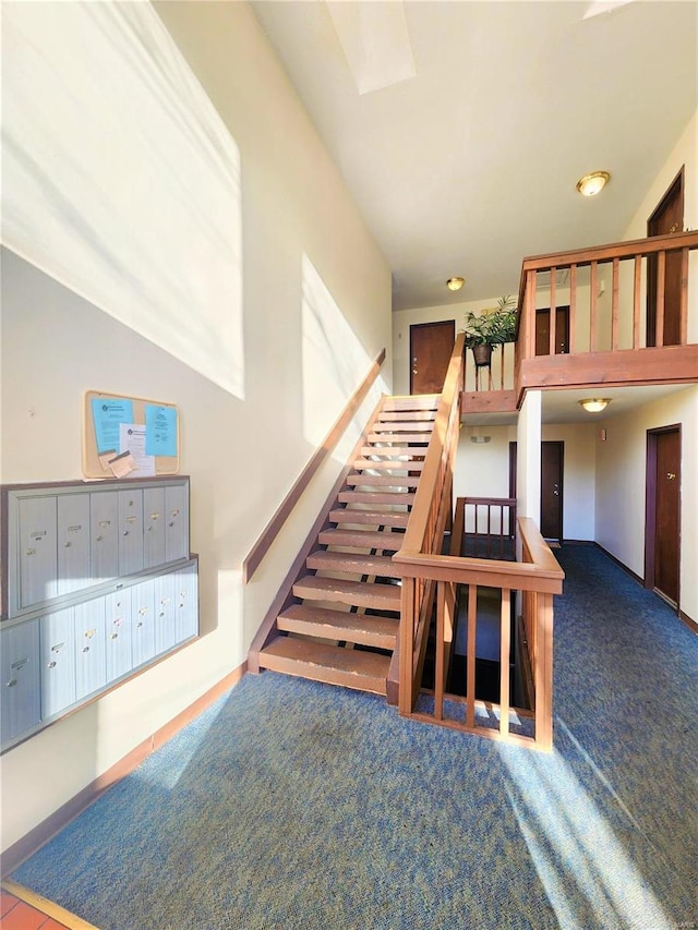 stairway featuring carpet flooring and a mail area