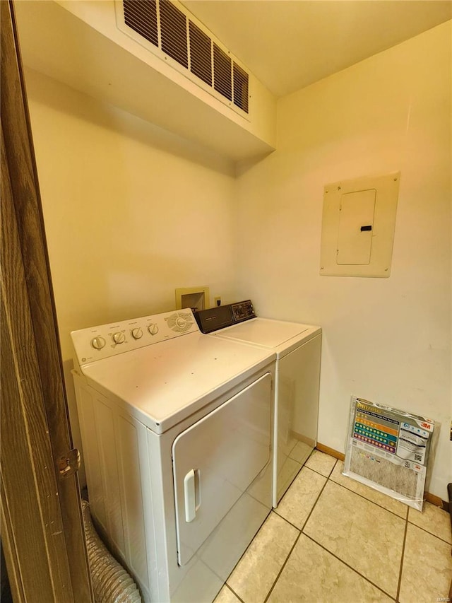 washroom featuring separate washer and dryer, electric panel, and light tile patterned floors