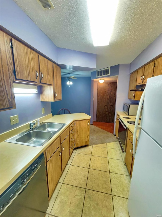 kitchen with a textured ceiling, sink, kitchen peninsula, white appliances, and light tile patterned floors