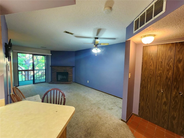 carpeted dining space featuring ceiling fan, a textured ceiling, and a fireplace