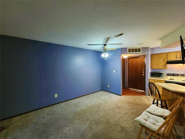 kitchen with light carpet, a textured ceiling, stainless steel microwave, and electric range