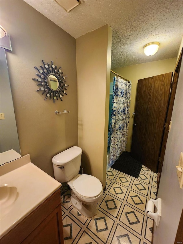 bathroom with a textured ceiling, curtained shower, toilet, and vanity