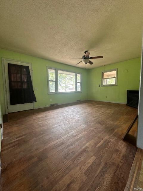 unfurnished living room featuring a textured ceiling, ceiling fan, and dark hardwood / wood-style flooring