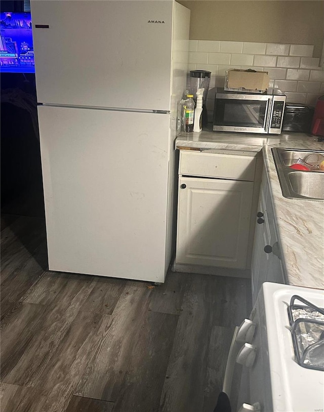 kitchen with dark wood-type flooring, sink, backsplash, white cabinets, and white fridge