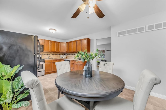 tiled dining area with ceiling fan and sink