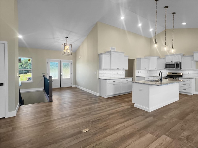 kitchen featuring white cabinetry, an island with sink, dark hardwood / wood-style flooring, pendant lighting, and stainless steel appliances