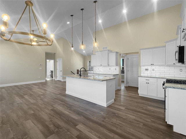 kitchen with hanging light fixtures, a kitchen island with sink, and white cabinetry