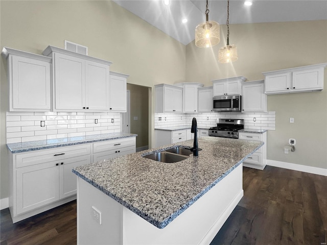 kitchen featuring appliances with stainless steel finishes, a kitchen island with sink, white cabinetry, and decorative light fixtures