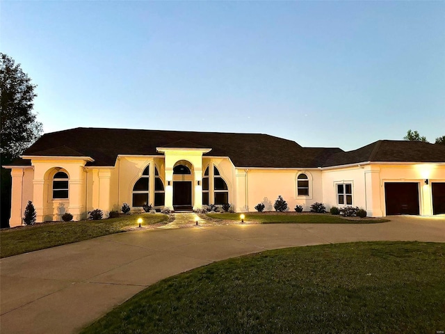 mediterranean / spanish-style home featuring a lawn and a garage