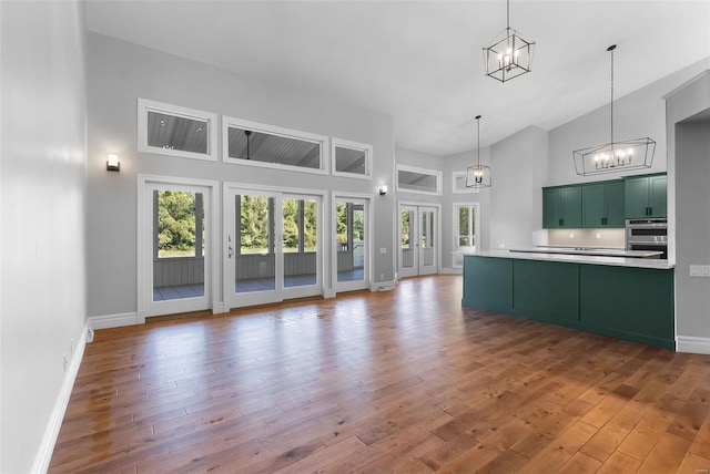 kitchen with pendant lighting, high vaulted ceiling, green cabinets, and wood-type flooring