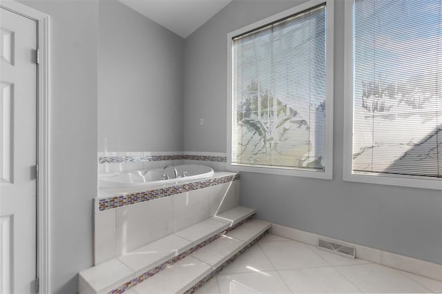 bathroom with tiled bath, lofted ceiling, and tile patterned floors