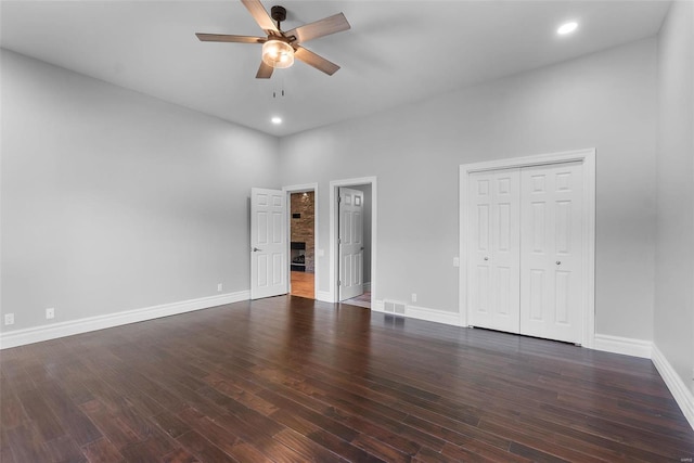 unfurnished bedroom with ceiling fan, a closet, dark hardwood / wood-style floors, and a high ceiling