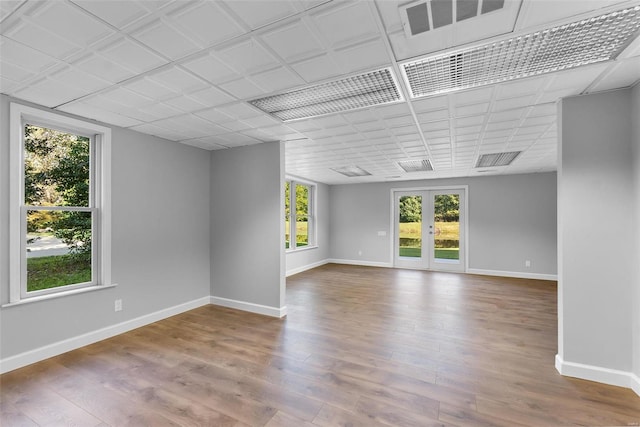 spare room with a healthy amount of sunlight, hardwood / wood-style floors, and french doors