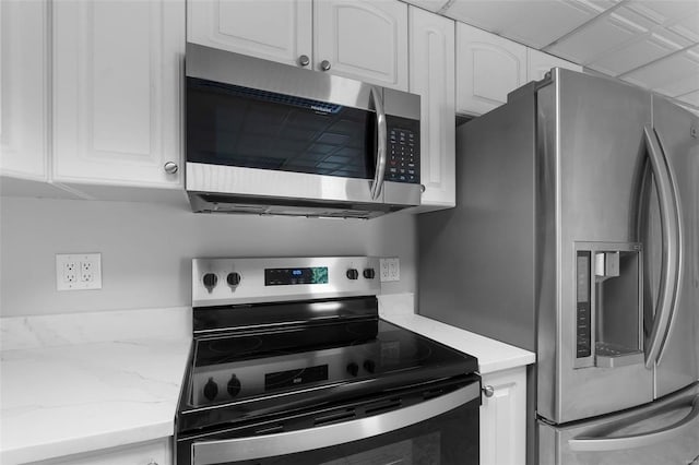 kitchen with light stone countertops, white cabinetry, and stainless steel appliances