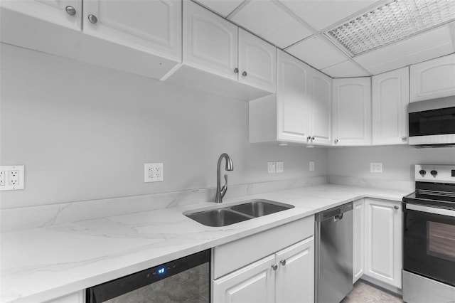 kitchen featuring light stone countertops, stainless steel appliances, sink, and white cabinetry