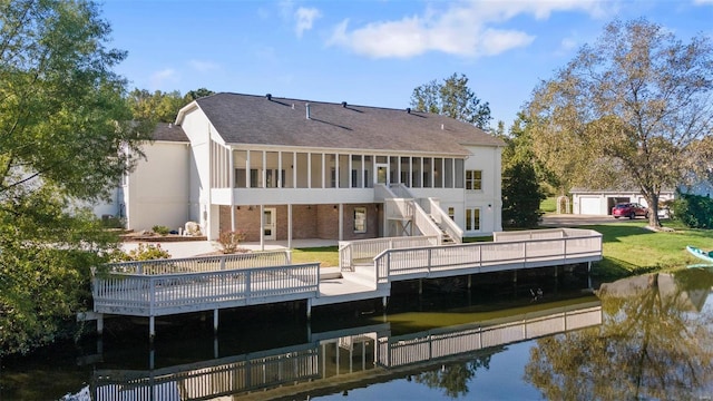 rear view of property with a yard, a patio, and a deck with water view