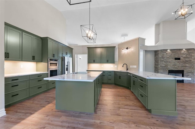 kitchen featuring green cabinetry, decorative light fixtures, and high vaulted ceiling