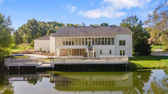 rear view of house featuring a yard and a deck with water view