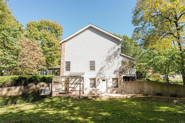 back of house featuring a deck, a yard, and a sunroom