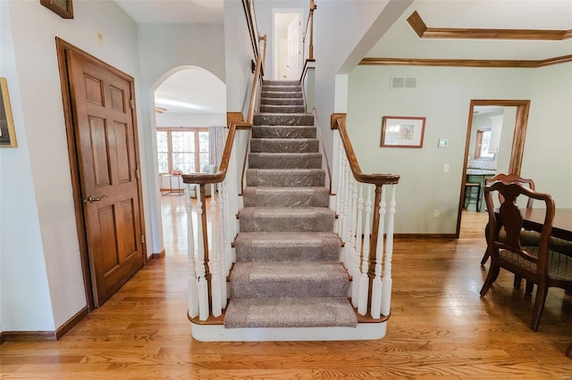 stairs featuring wood-type flooring and ornamental molding