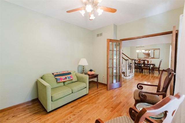 living area with ceiling fan with notable chandelier and wood-type flooring