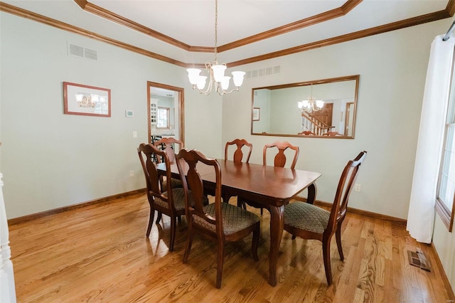 dining area featuring light hardwood / wood-style flooring, ornamental molding, and a notable chandelier